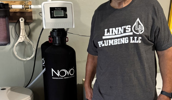 A Linn's Plumbing professional standing next to a Novo water softener system